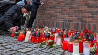 Lidé od pátku na pietních místech pokládají květiny zapalují svíčky.