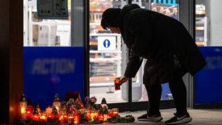 Žena pokládá svíčku před obchodem, kde po útoku nožem zemřely dvě ženy